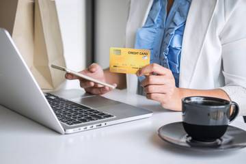 Young woman consumer holding smartphone, credit card and typing on laptop for online shopping and payment make a purchase on the Internet, Online payment, networking and buy product technology