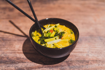 vegan singapore noodles with veggies and warm curry soup bowl with chopsticks