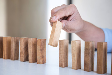 Risk and Strategy in Business, Image of hand gambling placing wooden block on a line of domino,...