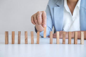 Risk and Strategy in Business, Image of hand gambling placing wooden block on a line of domino,...