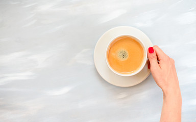 girl's hands with red manicure holding coffee cup, flat lay, top view