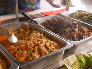 Selective focus of Thai panang curry with pork ( Panang Moo ), one of many Thai prepared street foods ( Kao Rad Geng ), and other menus in a display glass cabinet, ready to be served