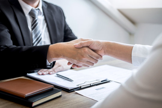 Employer in suit and new employee shaking hands after good deal interview