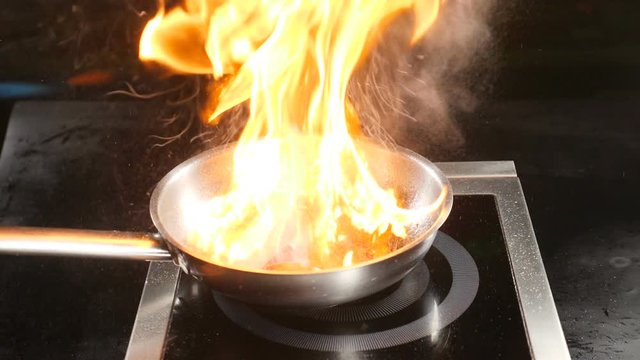 Chef cooking flambe dish in restaurant kitchen. Italian cuisine. Food video in slow motion. Magnificent flame over frying pan. Flambe fruit dessert. hd