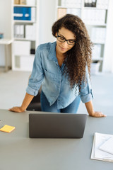 Casual businesswoman standing reading a laptop