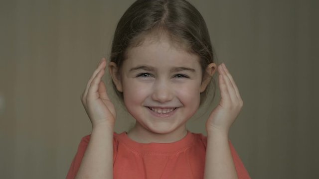 Girl playing hide and seek portrait.  Cute little girl open her face with hands. Playing hide and seek, peek a boo. Closeup.