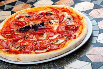 Diabola pizza with chorizo and chili. Spicy dish. On the stone table