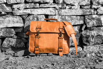 Brown old style handmade leather bag against black and white stone wall