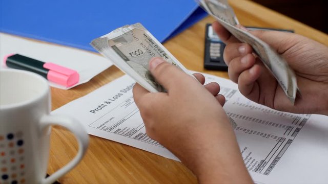 An accountant counts Rupee 500 Indian currency notes and note it down. 