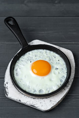 fried eggs in cast iron pan on white wooden stand.