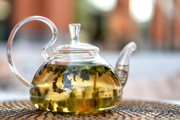 glass teapot with fresh green tea on street cafe table