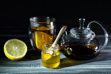 honey, lemon and black tea in thermostat on black wooden table. Tea ceremony