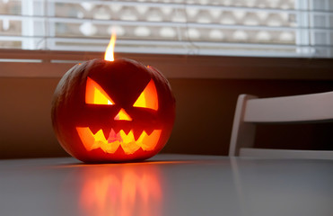 Halloween October holiday celebration symbol, scary pumpkin on kitchen table glowing from inside