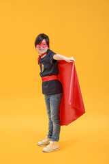 Cute little girl dressed as superhero on color background