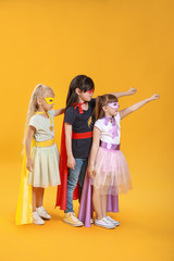 Cute little children dressed as superheroes on color background