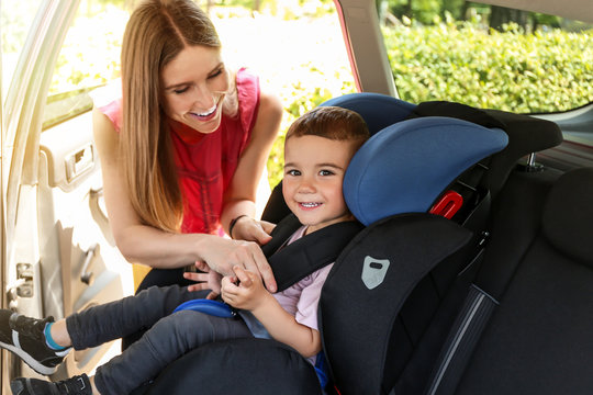 Mother Buckling Her Little Son In Car Seat