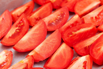 Homemade dried red  tomatoes slices with basil oregano spices cooking process. Traditional Italian Mediterranean kitchen cuisine.