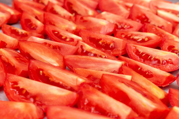 Homemade dried red  tomatoes slices with basil oregano spices cooking process. Traditional Italian Mediterranean kitchen cuisine.