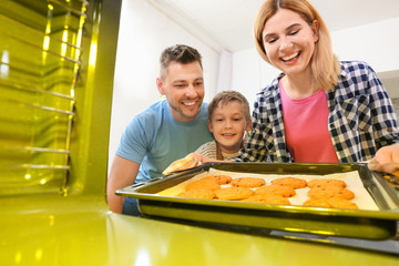 Family taking baking tray with cookies out of oven