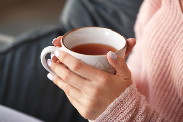 Beautiful young woman drinking tea at home, closeup
