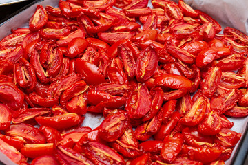 Homemade dried red  tomatoes slices with basil oregano spices cooking process. Traditional Italian Mediterranean kitchen cuisine.