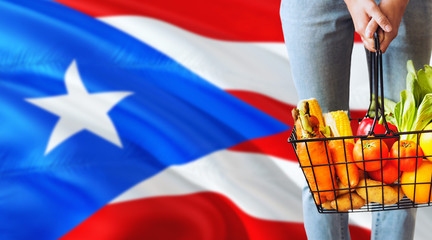 Woman is holding supermarket basket, Puerto Rico waving flag background. Economy concept for fresh...