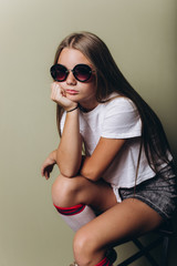 Close up portrait of young girl with long hair in sun glasses posing in studio