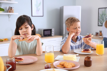 Funny little children eating tasty toasts in kitchen