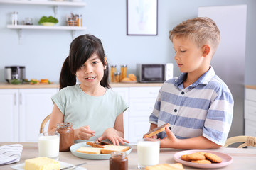 Obraz na płótnie Canvas Funny little children eating tasty toasts in kitchen