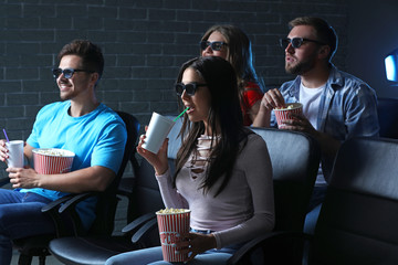 Friends with popcorn watching movie in cinema