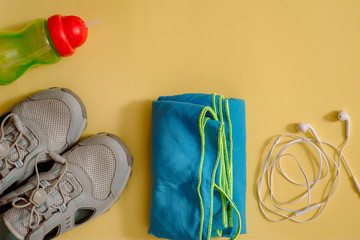 Athlete's set with female clothing, dumbbells and bottle of water on yellow background