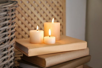 Fototapeta na wymiar Beautiful burning candles and books on table