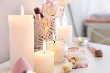 Obraz na płótnie Canvas Beautiful burning candles and cosmetics on dressing table, closeup