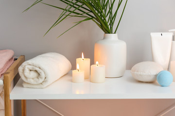 Beautiful burning candles and cosmetics on stand in bathroom