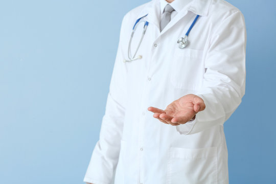 Male Doctor Holding Something Against Color Background