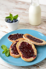 Plate with tasty toasted bread and jam on white table