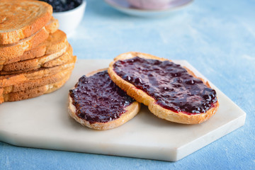 Board with tasty toasted bread and jam on table