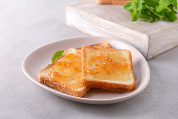 Plate with tasty toasted bread and jam on grey table