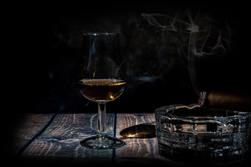 Glass of whiskey and cigar on black background