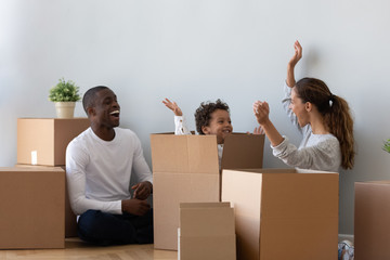 Happy mixed ethnicity family playing on moving day unpacking boxes