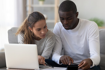 Interracial couple using calculator calculating paying domestic bills do paperwork