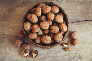 Walnuts in a round wicker basket on a wooden background. Top view. Copy, empty space for text