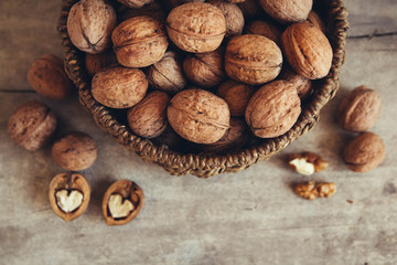 Walnuts in a round wicker basket on a wooden background. Top view. Copy, empty space for text