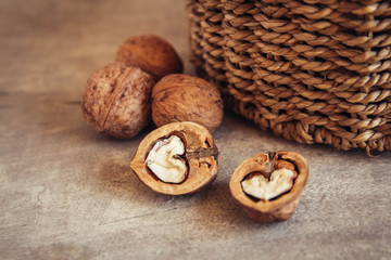 Walnuts in a round wicker basket on a wooden background. Place for your text