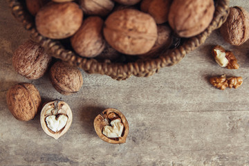 Walnuts in a round wicker basket on a wooden background. Top view. Copy, empty space for text