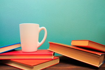  pile of old books with mug , panorma, good copy space  on blue background