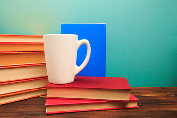Fototapeta na wymiar pile of old books with mug , panorma, good copy space on blue background