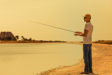 Young man fishing at sea from the shore. fisherman uses spinning
