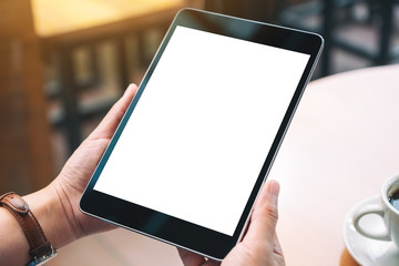 Mockup image of hands holding black tablet pc with blank white desktop screen