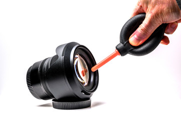 Blowing away dust and dirt from a camera lens with a rocket blower